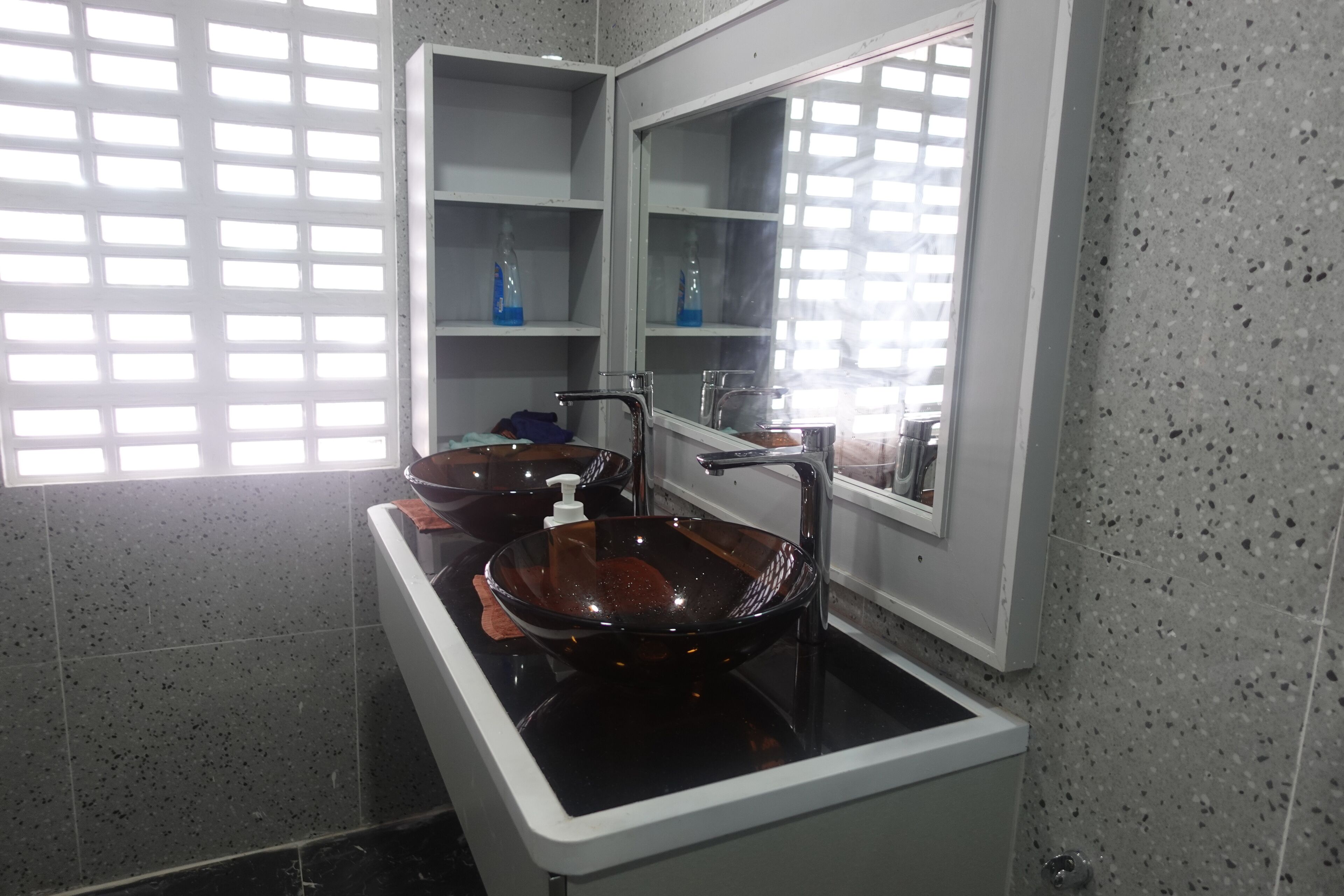 Un baño moderno con un lavabo de vidrio negro, encimera blanca y un espejo sobre el lavabo.