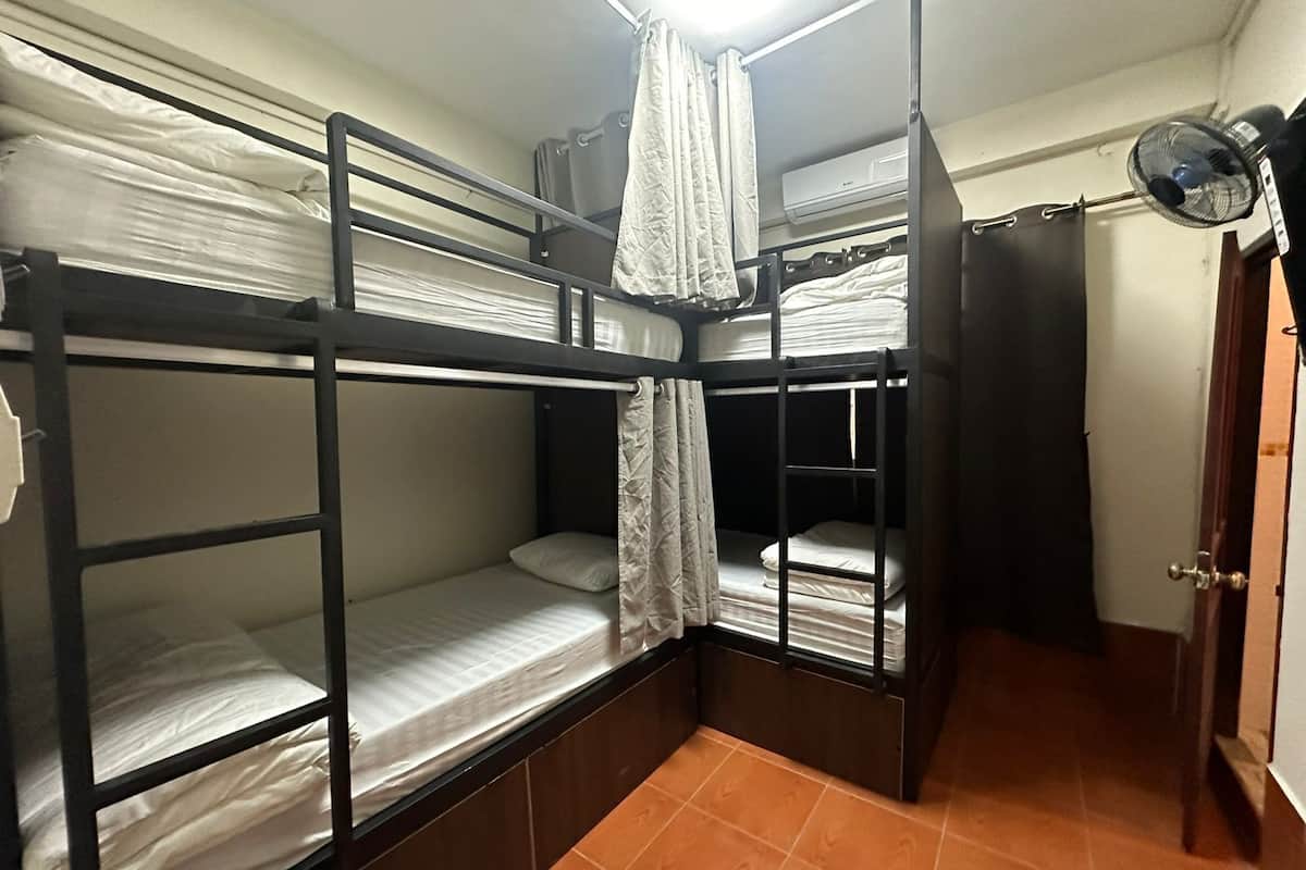 A compact room with bunk beds, a fan, and a door.