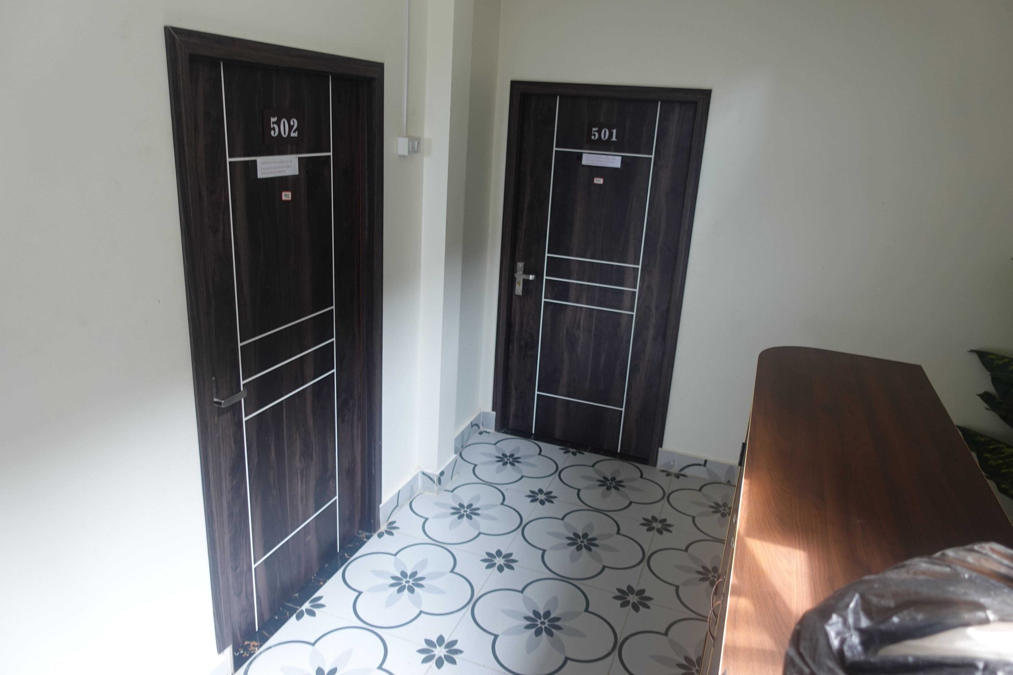 A hallway with two doors labeled 502 and 501, a patterned floor, and a wooden bench.