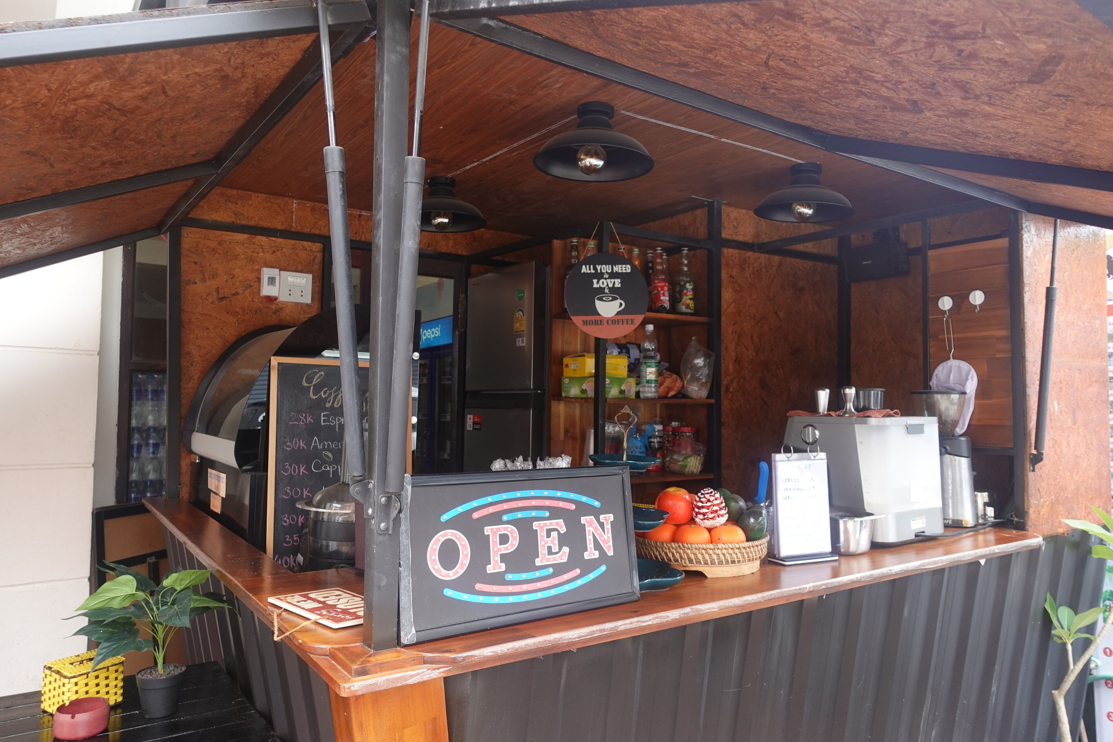 A coffee shop with an 'OPEN' sign, a menu board, and a variety of coffee-making equipment.