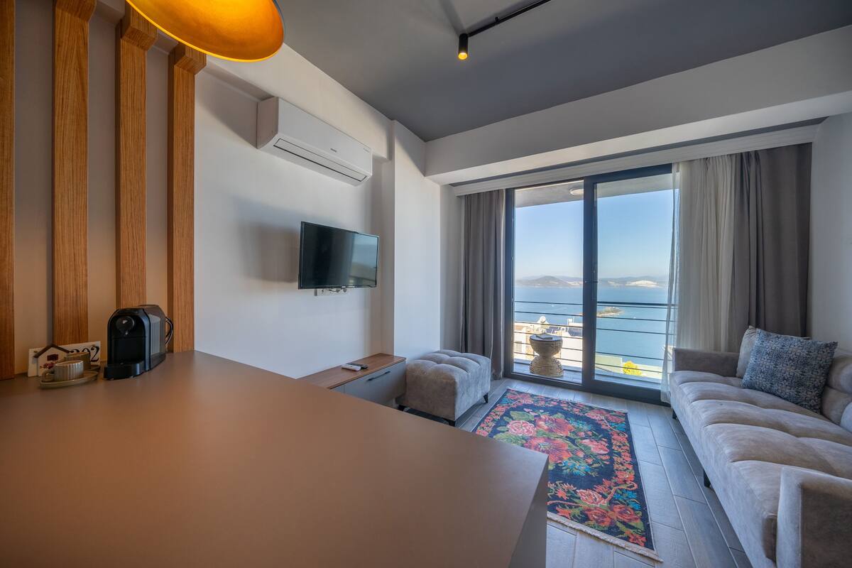 Un salon moderne avec un canapé, une table basse, un téléviseur et une vue sur la mer.
