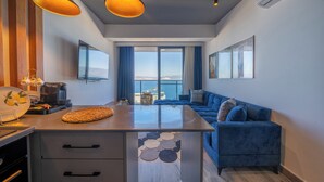 Una cocina moderna con comedor, un sofá azul y un ventanal con vista al mar.