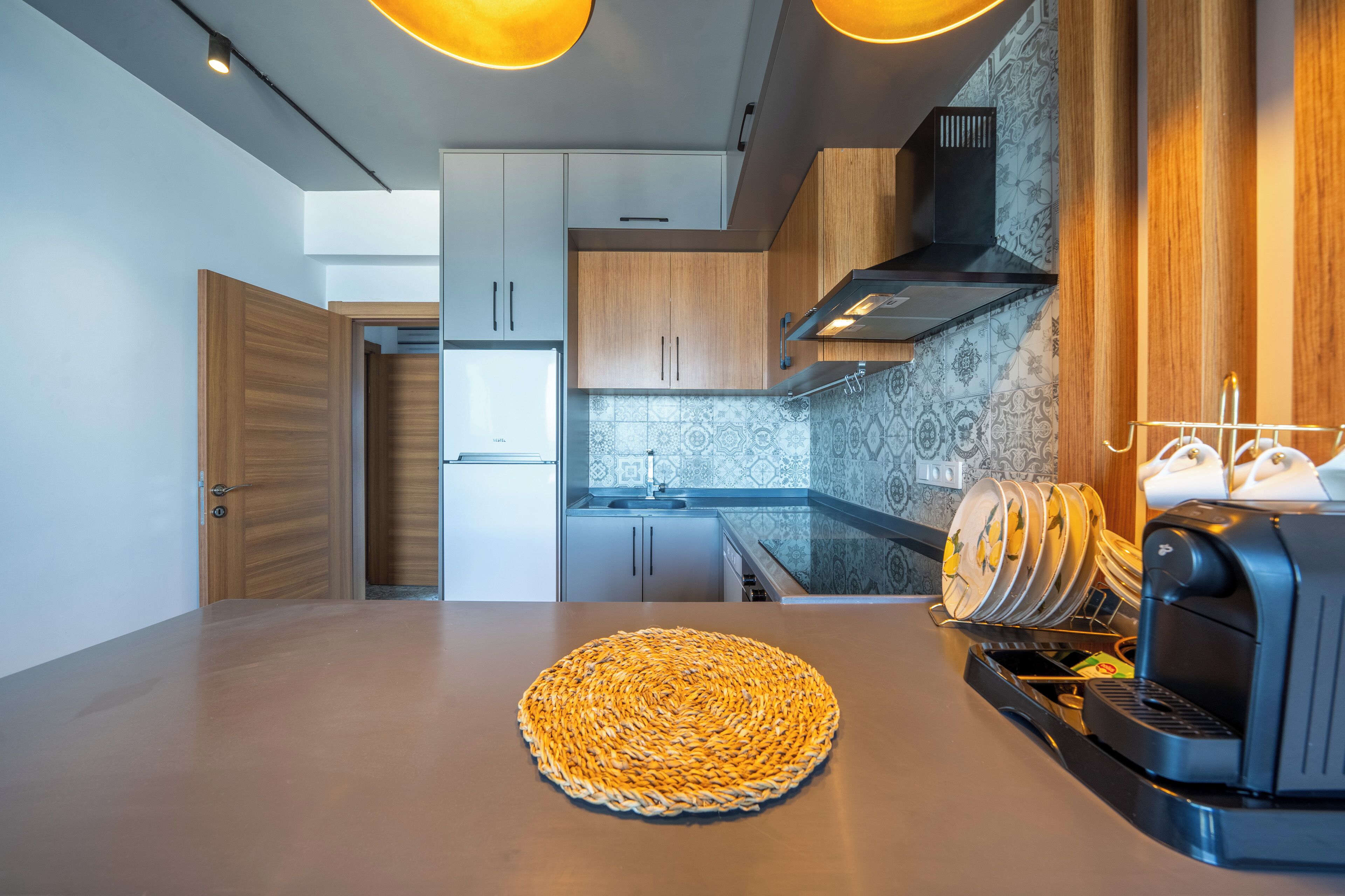 Une cuisine moderne avec des meubles en bois, un four encastré et une machine à café.