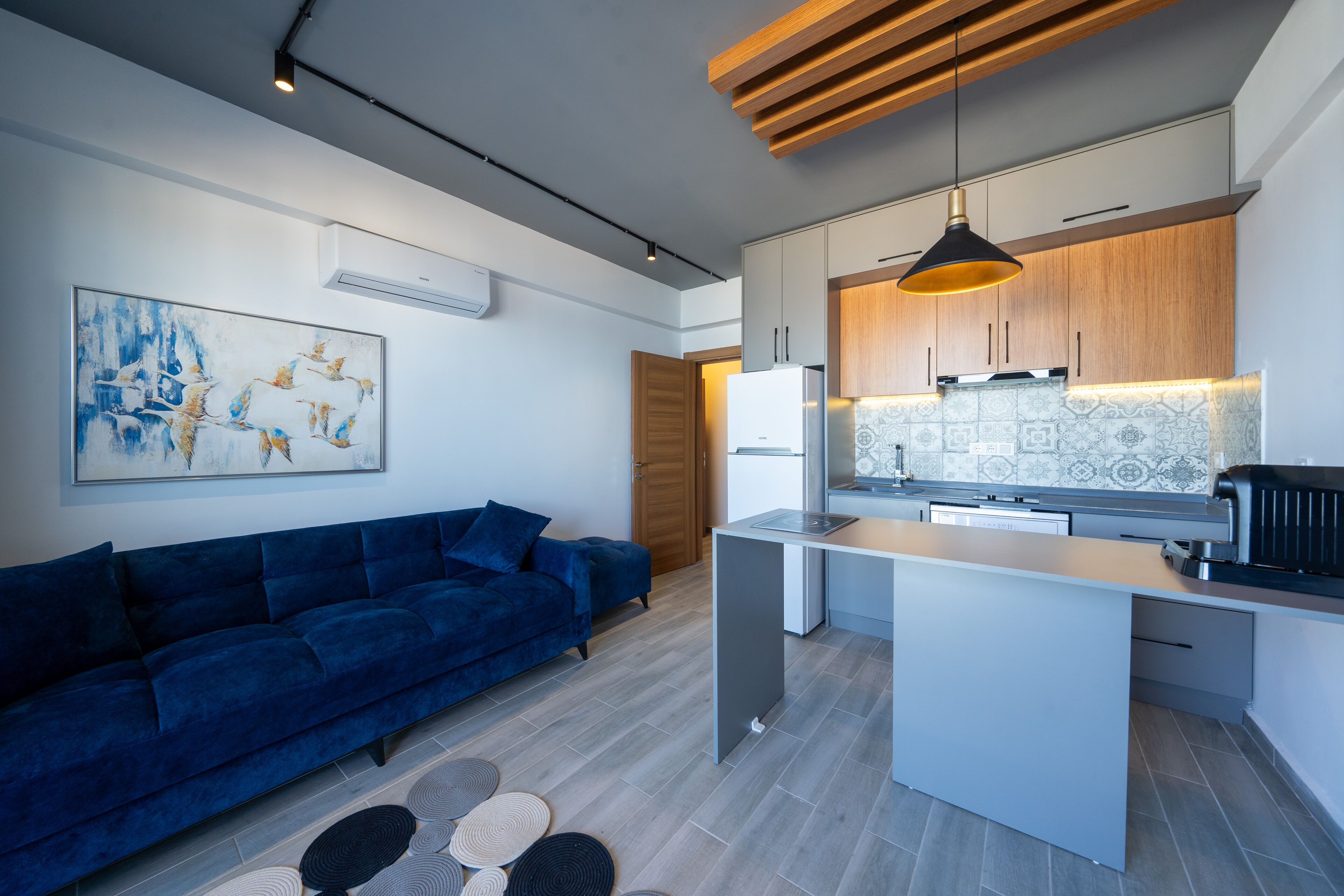 A modern kitchen with a central island, wooden cabinets, and a pendant light.
