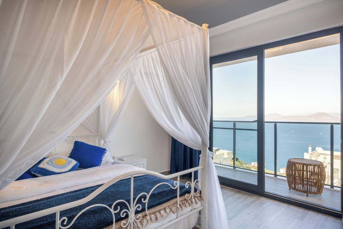 Un balcon avec un lit, une chaise en osier et une vue sur la mer.