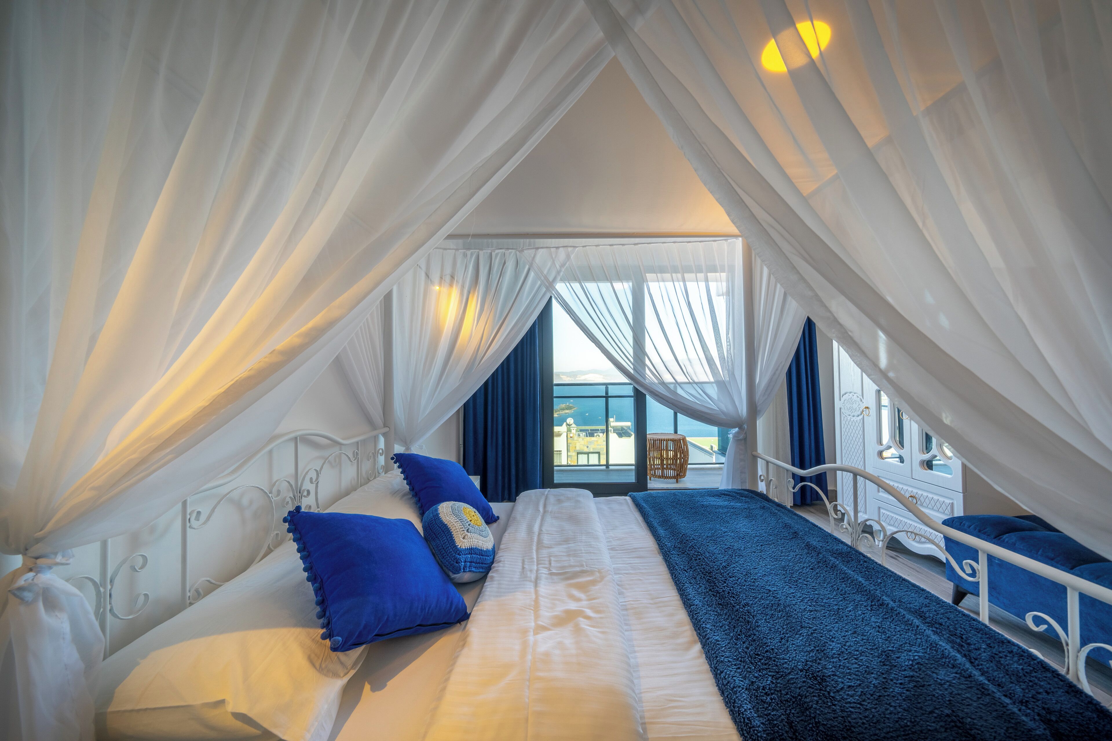 Un dormitorio con cama a dosel, vistas de la ciudad y un balcón con una silla.