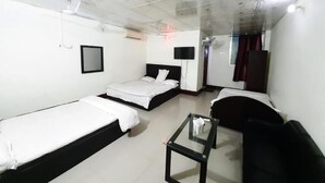 A hotel room with two single beds, a sofa, a small table, and a TV.