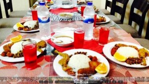 A dining table with plates of food, water bottles, and red glasses.