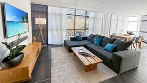 A modern living room with a large sofa, a coffee table, a TV, and a dining area with a table and chairs. - Dolce Vita in the Swiss Alps - Close to 4 Valleys (Martigny)