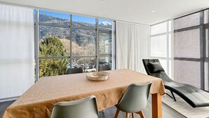 A modern dining area with a table and chairs, large windows offering a view of a mountainous landscape. - Dolce Vita in the Swiss Alps - Close to 4 Valleys (Martigny)