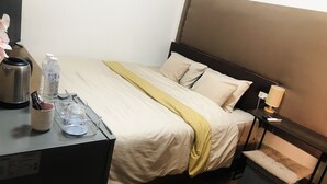 Une chambre d’hôtel comprenant un lit, une table de chevet, une lampe et un petit coin salon.