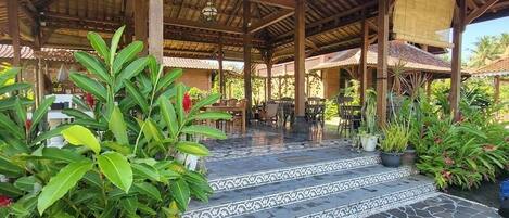 A covered outdoor area with a tiled floor and steps leading to a seating area.