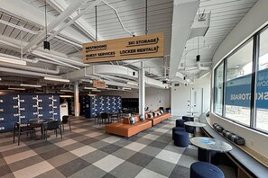A spacious lobby with a checkered floor, seating areas, and a ski storage sign indicating amenities.