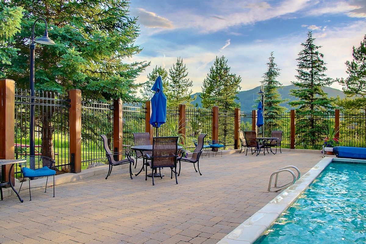 An outdoor pool area with a fence, chairs, and umbrellas.