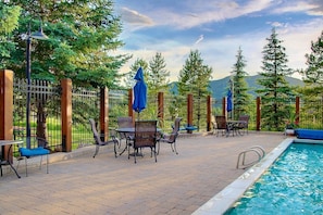 An outdoor pool area with a fence, chairs, and umbrellas. - Updated-SkiLocker-Heated Pool-HotTub-Near Free Bus (Steamboat Springs)