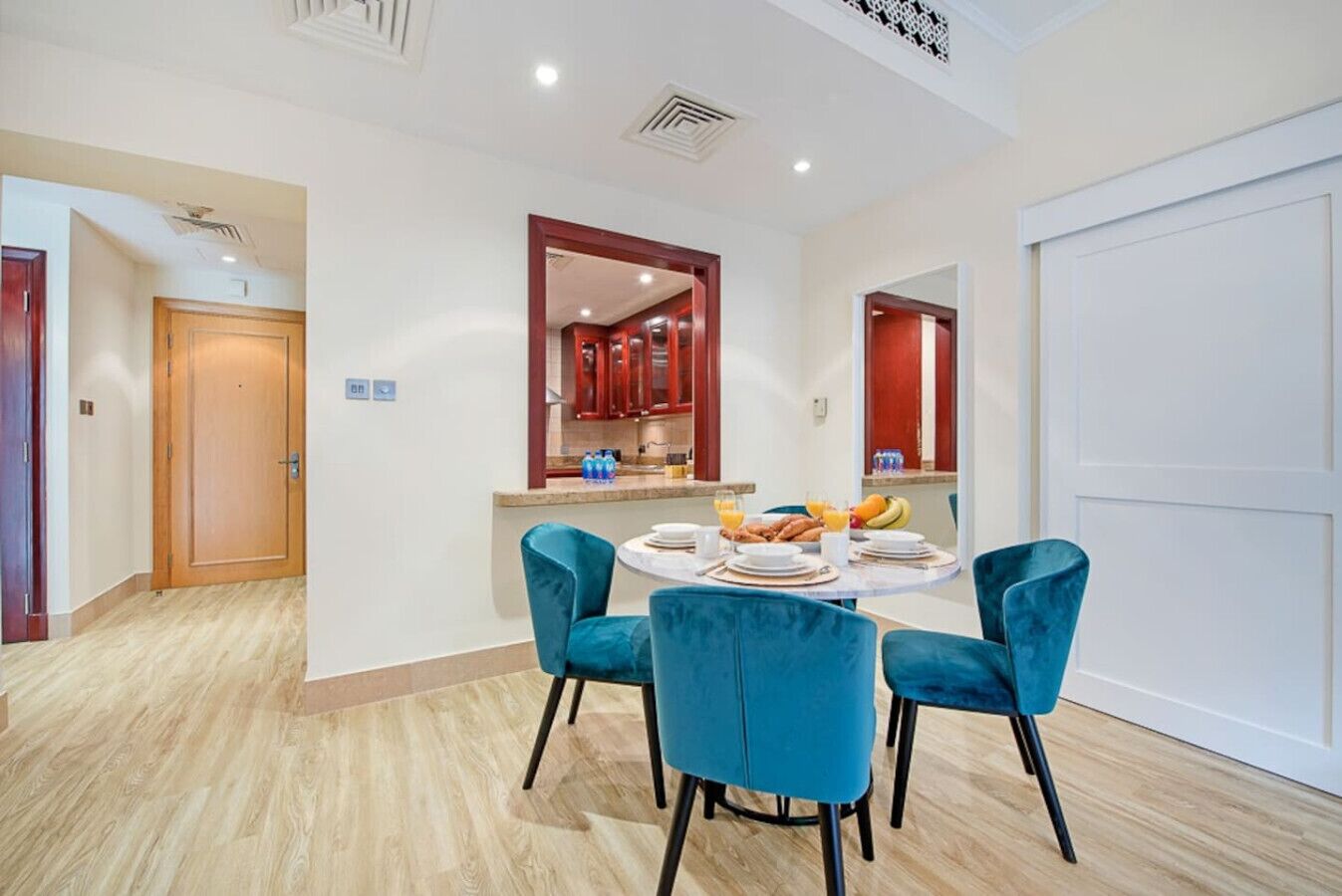Un comedor moderno con una mesa redonda, cuatro sillas azules y productos para el desayuno.