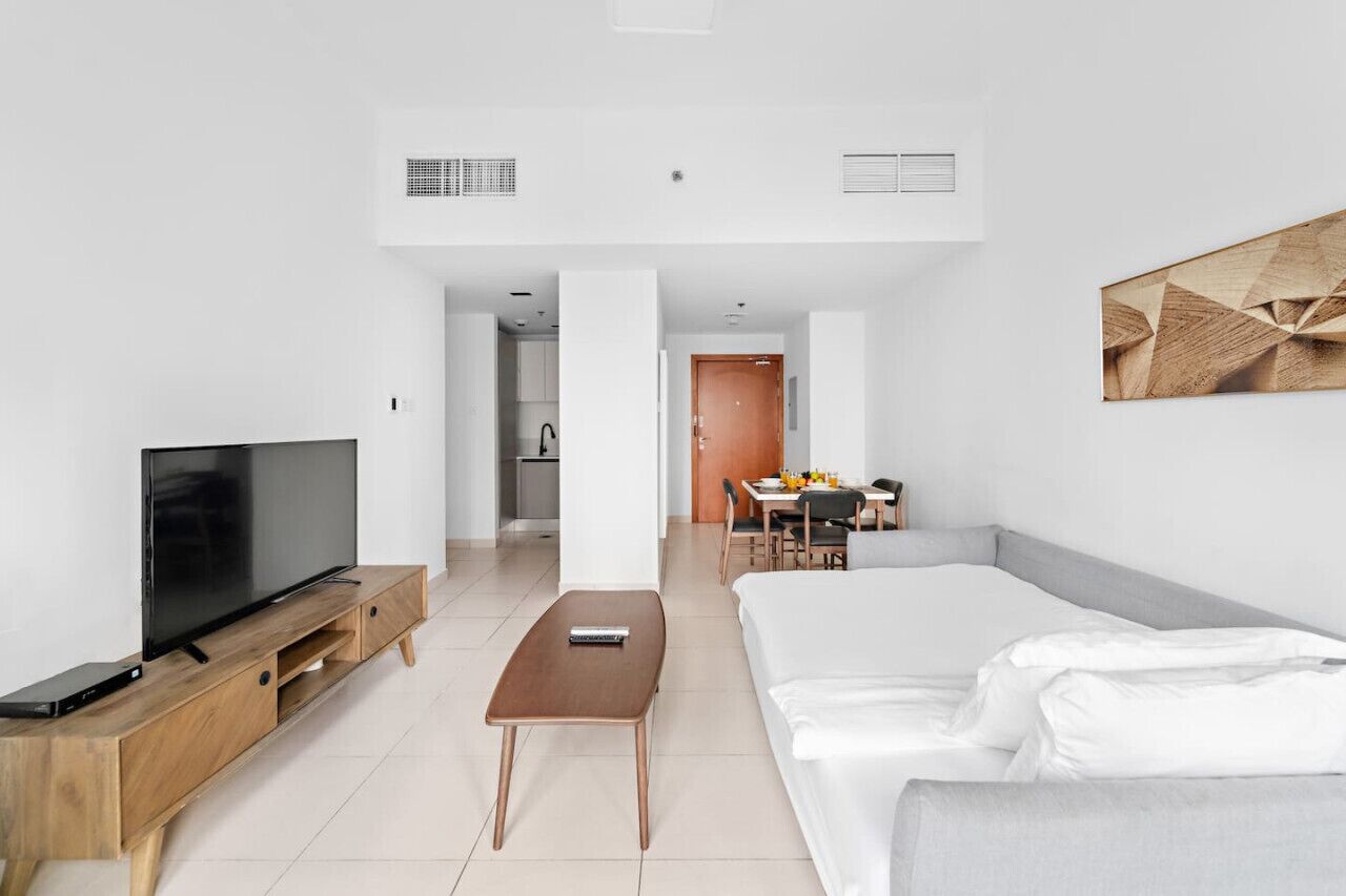 Ein modernes Hotelzimmer mit Flachbildfernseher, Holzmöbeln, einem Bett und einer Essecke.