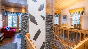 Un intérieur en bois agrémenté d’un mur en pierre, un coin repas avec une table et des chaises en bois, et un escalier avec des rampes en bois.