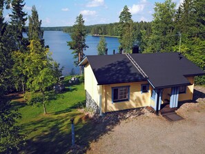 A single-story yellow house with a black roof, a visible chimney, and a small porch with blue trim. - Villa paasisalo by Interhome (Siilinjärvi)