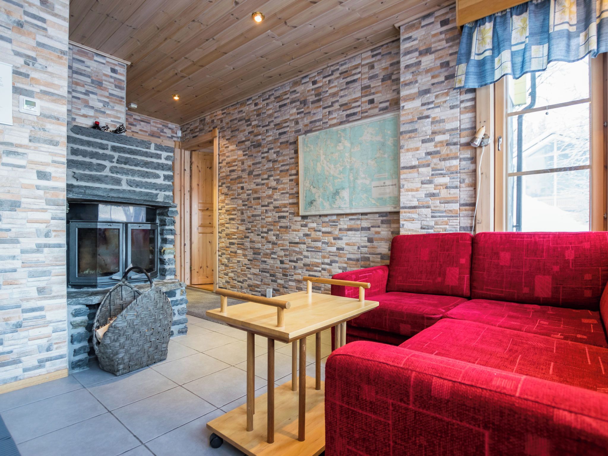 A cozy room with a stone fireplace, a red sofa, and a wooden table.