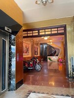 Um saguão de hotel com piso lustroso, uma scooter vermelha e uma escada que leva à área de recepção.