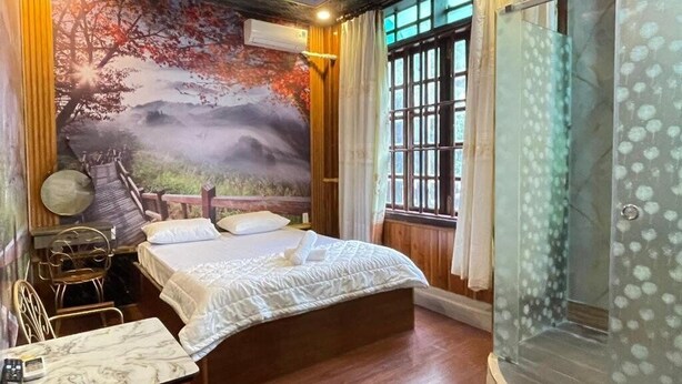 A bedroom with a bed, a desk, a chair, and a glass shower enclosure. - Hoang Gia Hotel Binh Duong by Bay Luxury (Ho Chi Minh City)