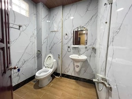 Uma casa de banho com sanita, lavatório e chuveiro.