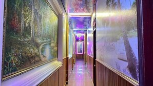 A corridor with a mural on the left and a large painting on the right, leading to a brightly lit room. - Hoang Gia Hotel Binh Duong by Bay Luxury (Ho Chi Minh City)