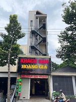 Um hotel chamado "KHÃCH SAN HOÃNG GIA", com entrada visível e escadaria que leva a um andar superior.