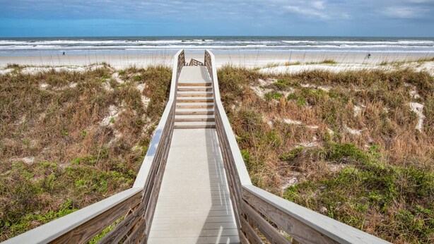 A wooden boardwalk leading to a beach with a clear view of the ocean. - Salty Shores (St. Augustine)