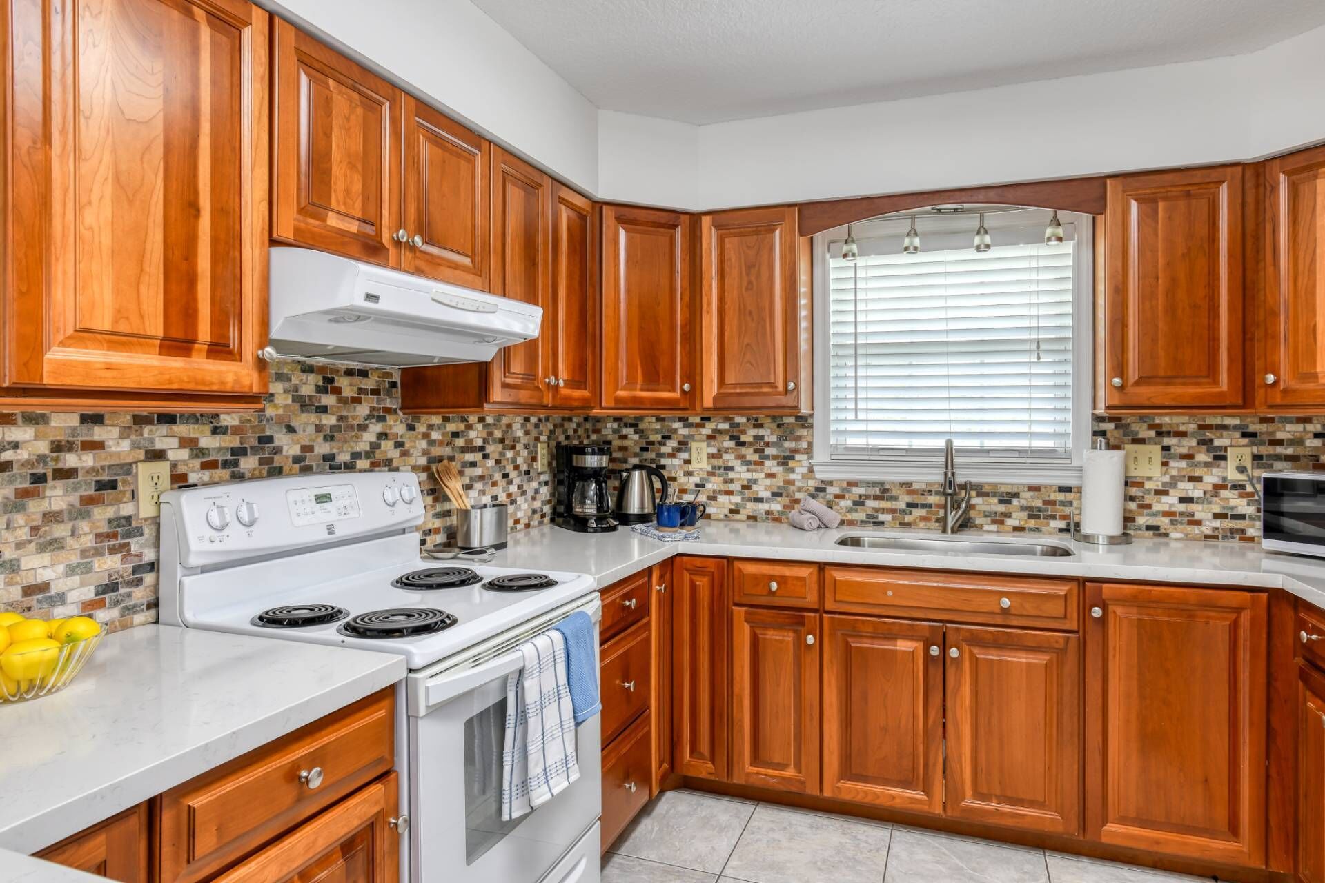 A kitchen with wooden cabinets, a white stove, and a tiled backsplash.