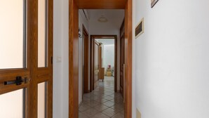 Um corredor com portas de madeira e chão de azulejos.