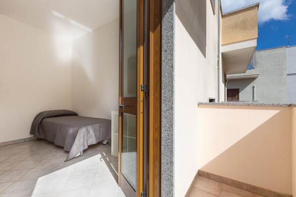 A bedroom with a bed, a sliding glass door, and a view of a balcony.