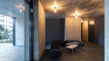 A modern interior with a concrete ceiling, a bench, a round table, and a glass wall.