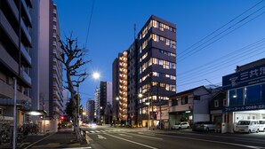 Une rue moderne d’une ville, au crépuscule, avec de hauts immeubles, un passage pour piétons et des véhicules garés.