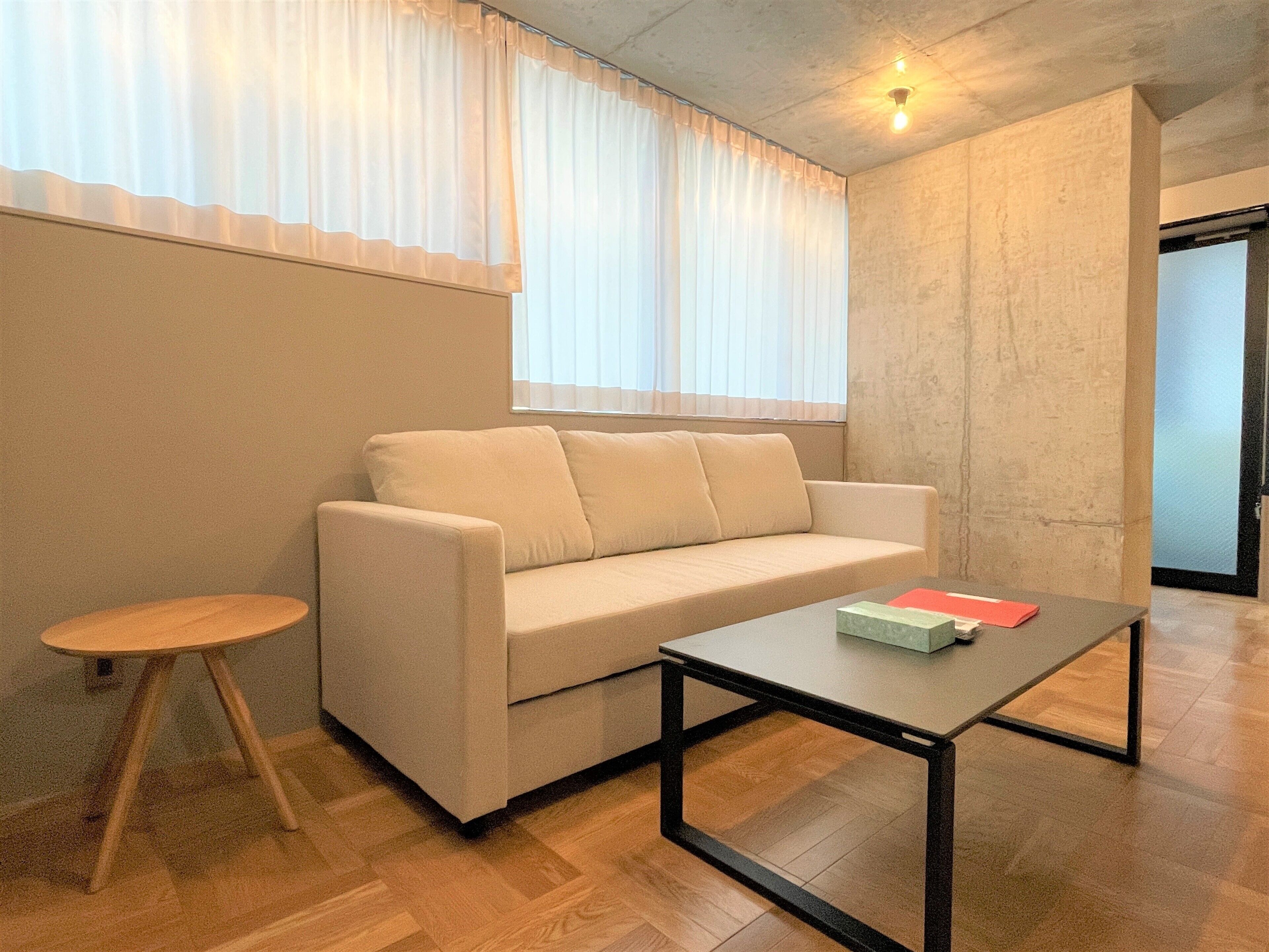 A modern living room with a beige sofa, a small round wooden table, and a coffee table.