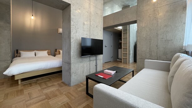 Une chambre d’hôtel moderne équipée d’un lit, d’un canapé, d’une télévision et d’une table basse.