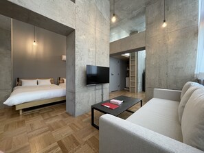 Ett modernt hotellrum med en säng, en soffa, en tv och ett soffbord.