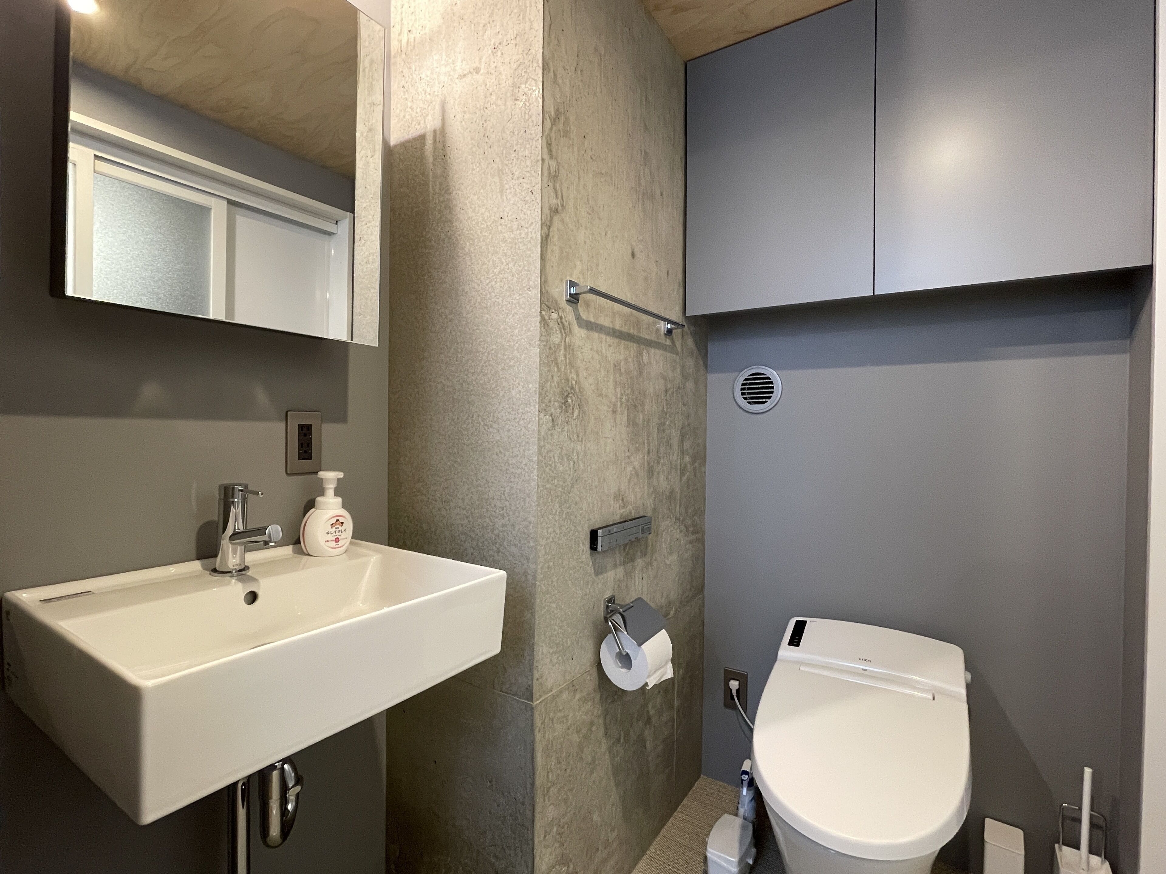 A modern bathroom with a white sink, a toilet, and a mirror above the sink.
