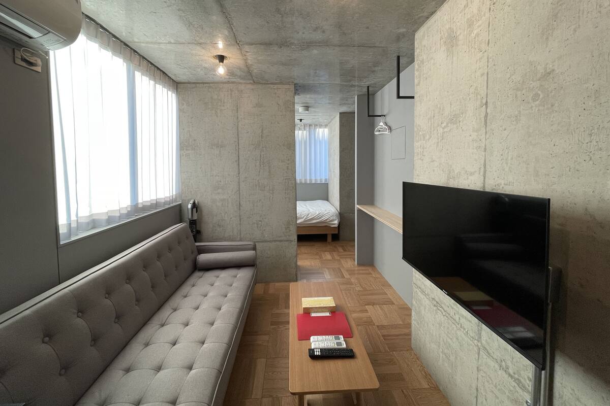 Quarto moderno com sofá, televisão, mesa de madeira e cama.