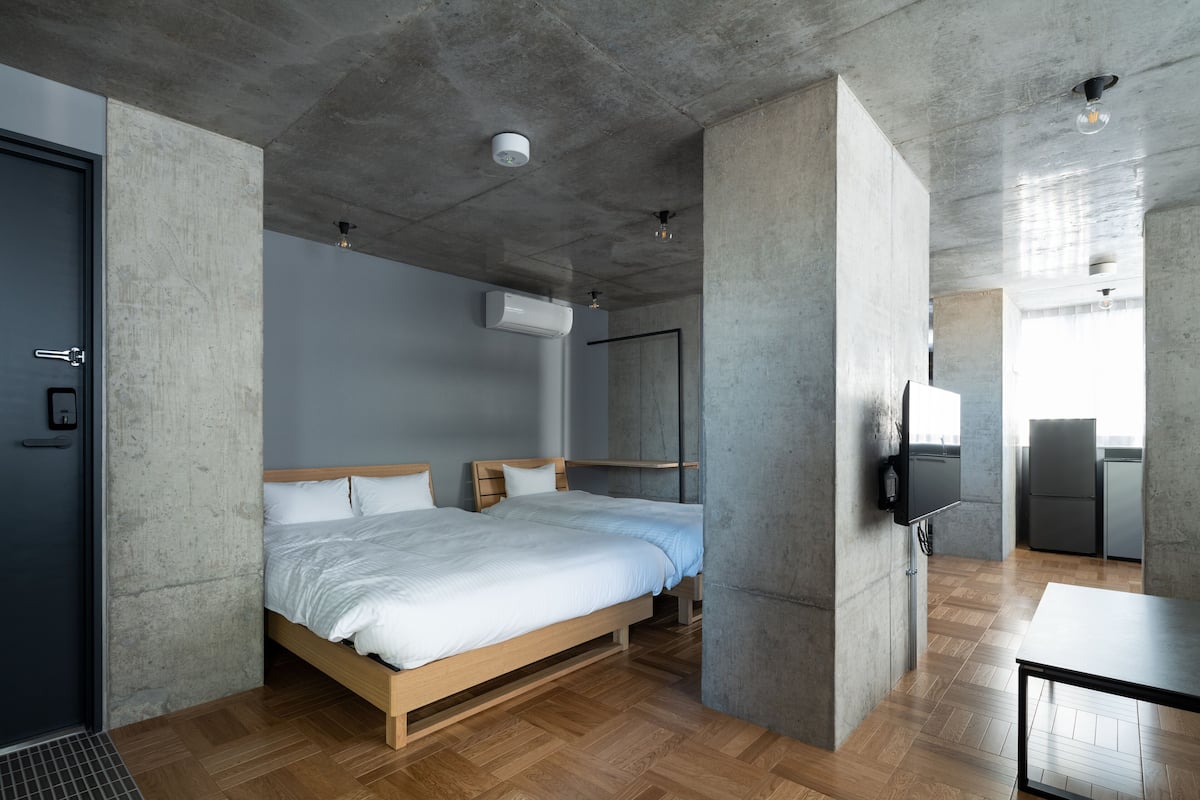 Quarto de hotel moderno com cama grande, televisão de tela plana e cozinha.