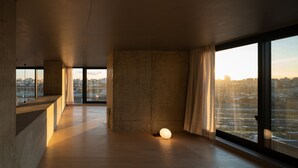 Un intérieur moderne avec de grandes fenêtres, un mur en béton et un luminaire sphérique.