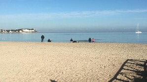 A beach with people relaxing, a sailboat in the distance, and a clear sky. - La Scalinatella in Mondello (Palermo)
