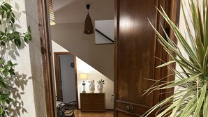 A hallway with a wooden door, a tiled floor, a bench, a cabinet, and a potted plant. - La Scalinatella in Mondello (Palermo)