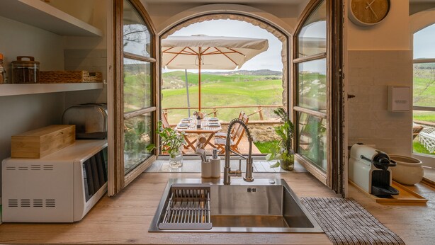 A kitchen with a view of a dining area, a sink, and a clock on the wall.