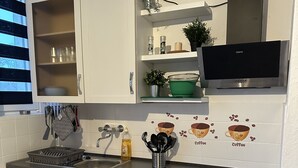 Una cucina moderna con mobili bianchi, elettrodomestici in acciaio inossidabile e una parete rivestita a tema caffè.