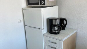 Una piccola cucina accessoriata con forno a microonde, macchina del caffè e frigorifero.