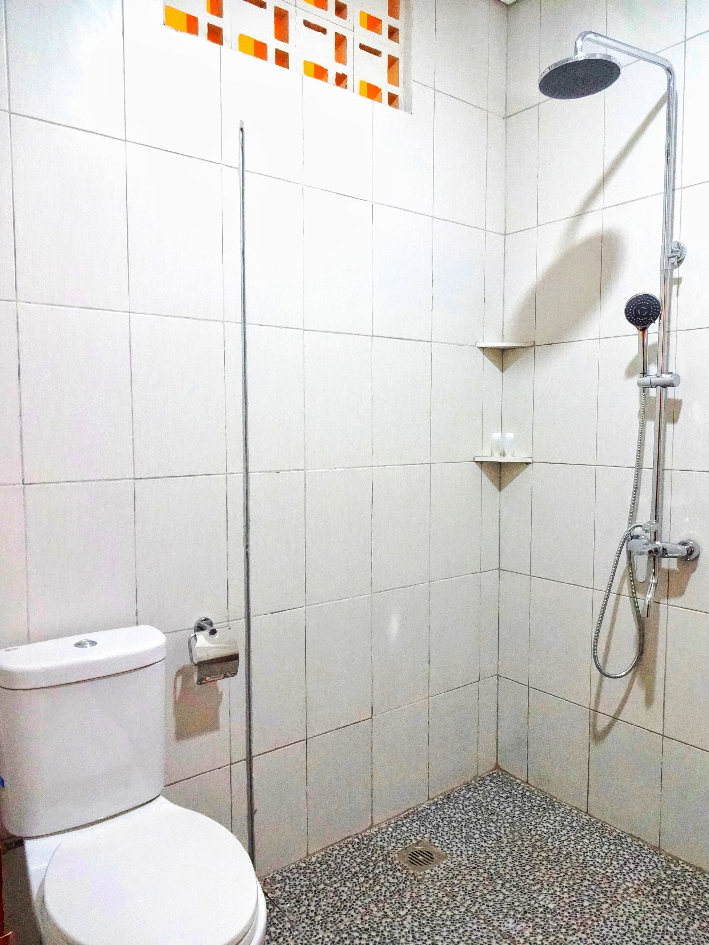 A small, tiled bathroom with a toilet, a shower, and a sink.
