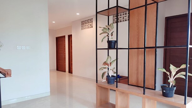 A hallway with a wooden bench, potted plants, and a black metal partition. - Ananda's Sanur (Denpasar)
