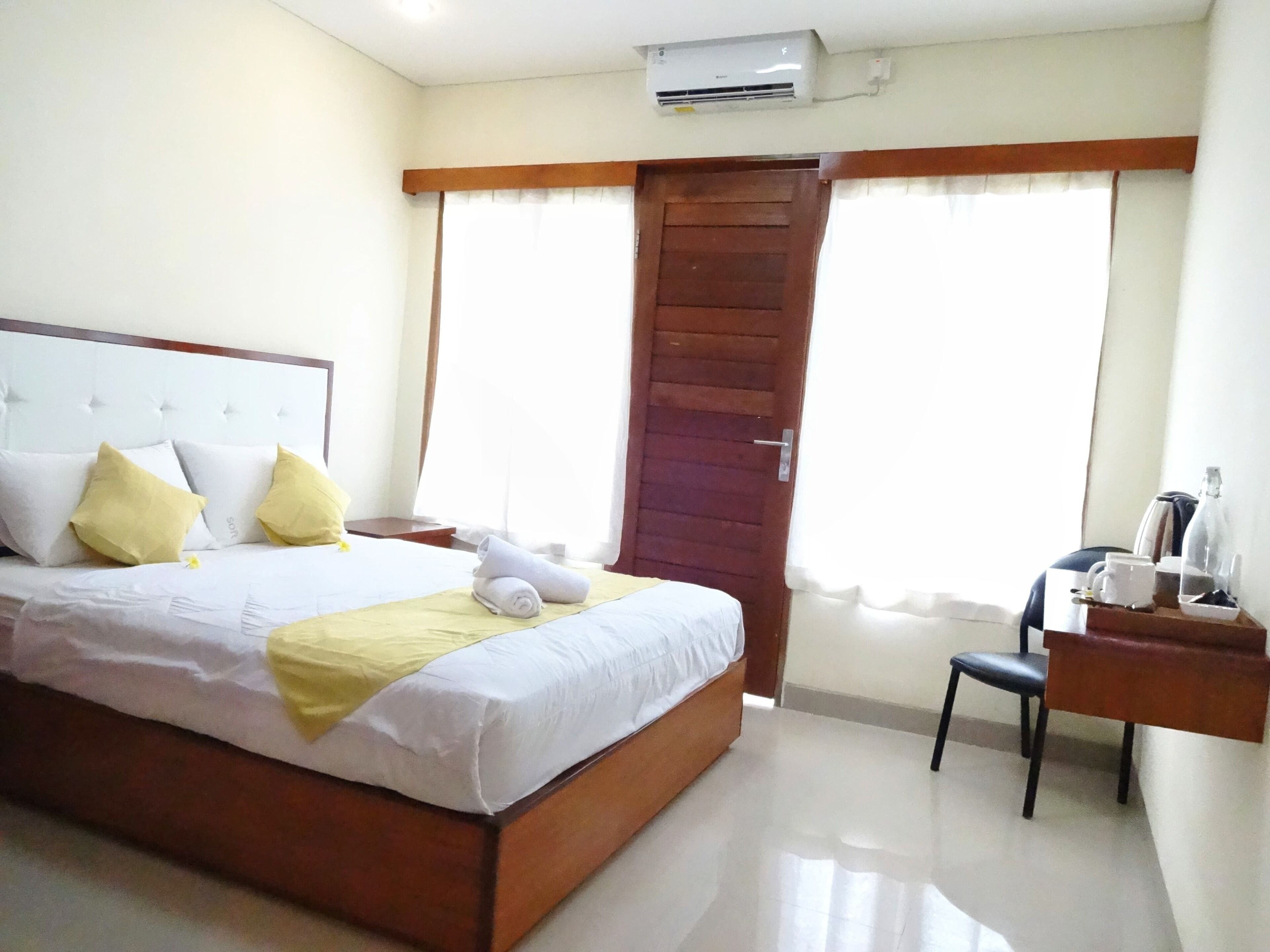 A hotel room with a bed, a desk, a chair, and a door.